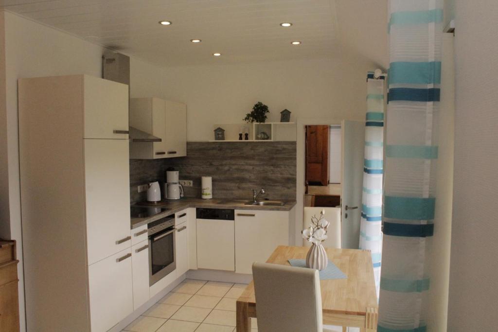 a kitchen with white cabinets and a table with a chair at Appartment Merle in Wimbach