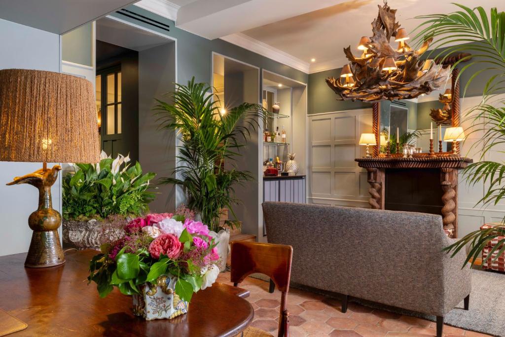 un salon avec une table avec des fleurs dessus dans l'établissement Hôtel Aubépine, à Paris