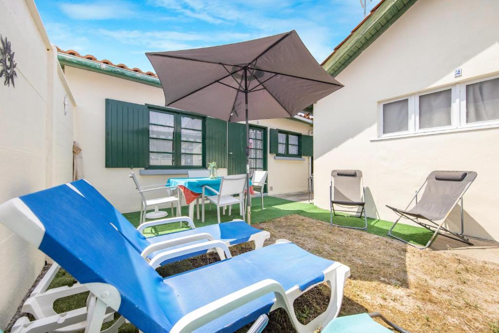 un patio avec une table, des chaises et un parasol dans l'établissement Villa Récompense Côte Atlantique n3, à Soulac-sur-Mer