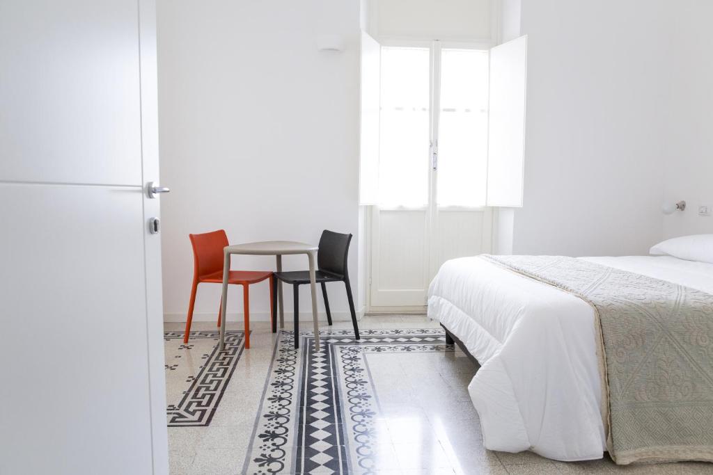 een slaapkamer met een bed en een tafel en stoelen bij B&B Angioy 18 in Cagliari