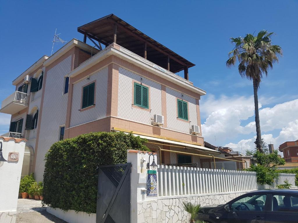 a house with a white fence and a palm tree at Albergo Villa Marina in Anzio