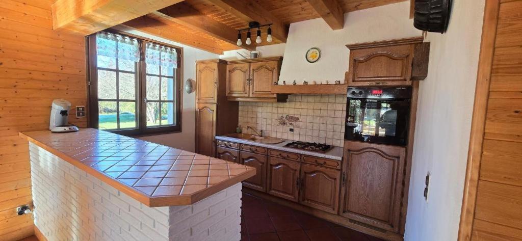 Una cocina con gabinetes de madera y encimera. en Gîte Douce Quiétude, en Barbey-Séroux