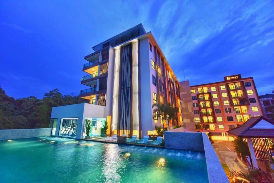 a hotel with a swimming pool in front of a building at Happy Place Official in Nai Yang Beach