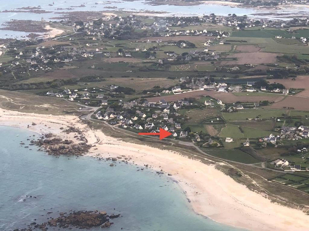 un avion rouge survole une plage dans l'établissement Maison du Crémiou en bord de mer, à Kerlouan