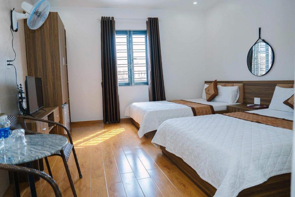 a hotel room with two beds and a table at Ngọc Bích Luxury in Cat Ba