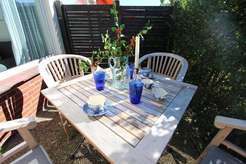 a wooden table with two chairs and blue glasses on it at Beachhouse in Langeoog