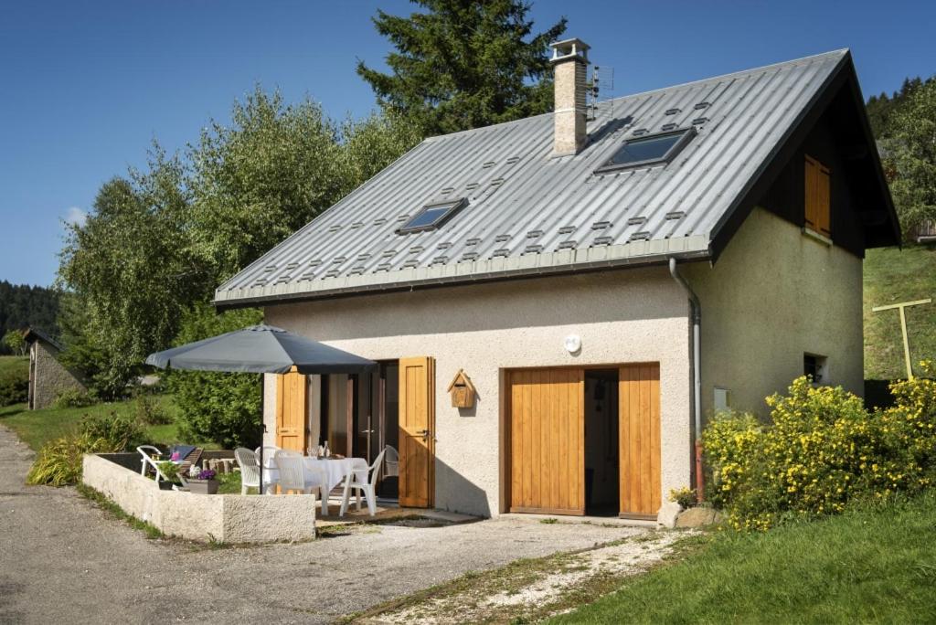 uma pequena casa com telhado inclinado e um pátio em Le Petit Nid - Chalet Corrençon em Corrençon-en-Vercors