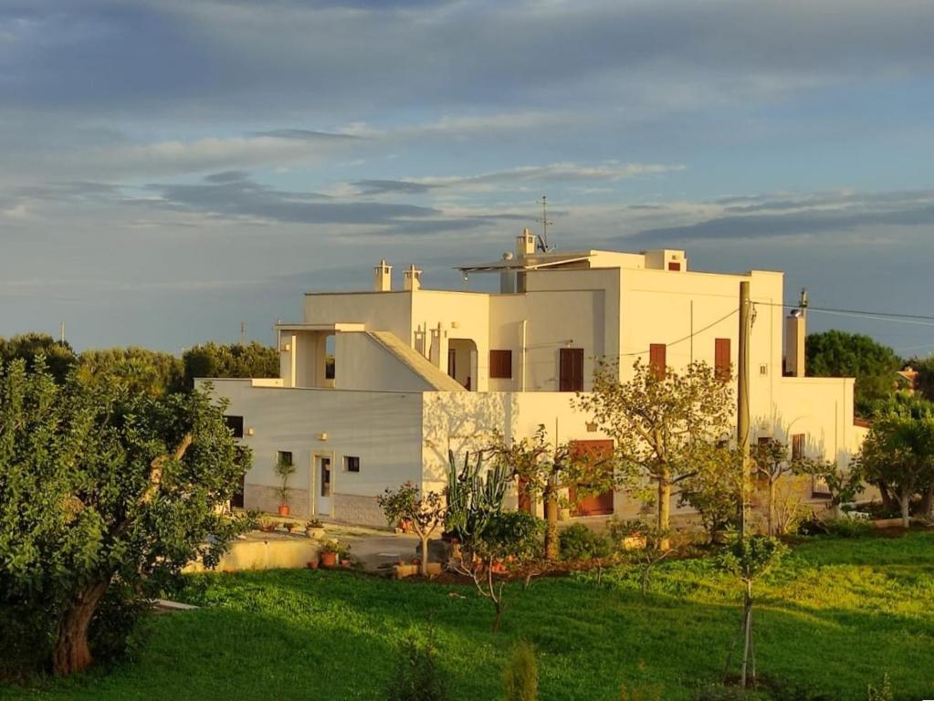 a large white house with trees in front of it at Residenza "I Tre Carrubi " in Fasano