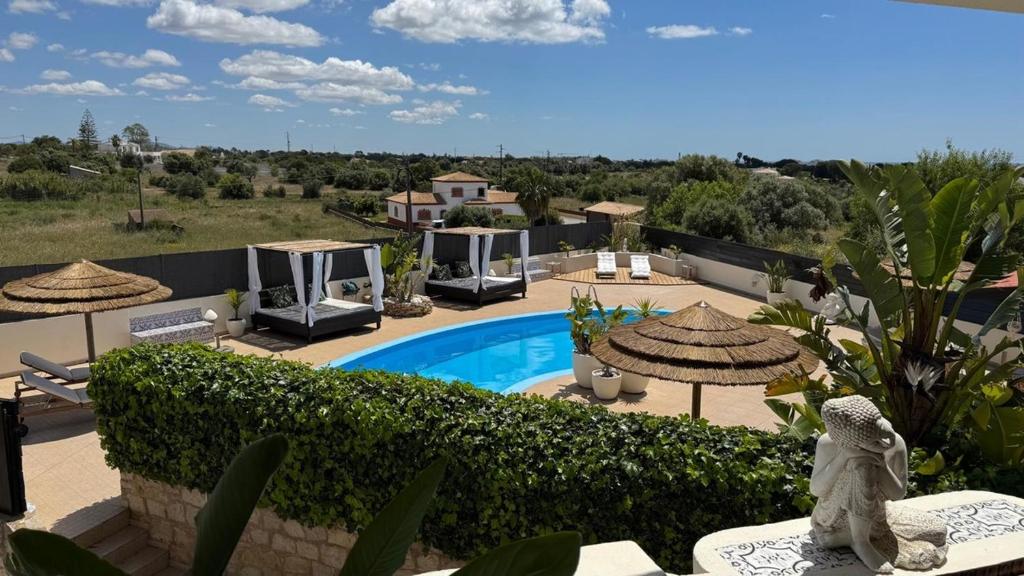 een villa met een zwembad en parasols bij Cegonha Villa powered by Cegonha Resort- Private swimming pool & air con in Albufeira