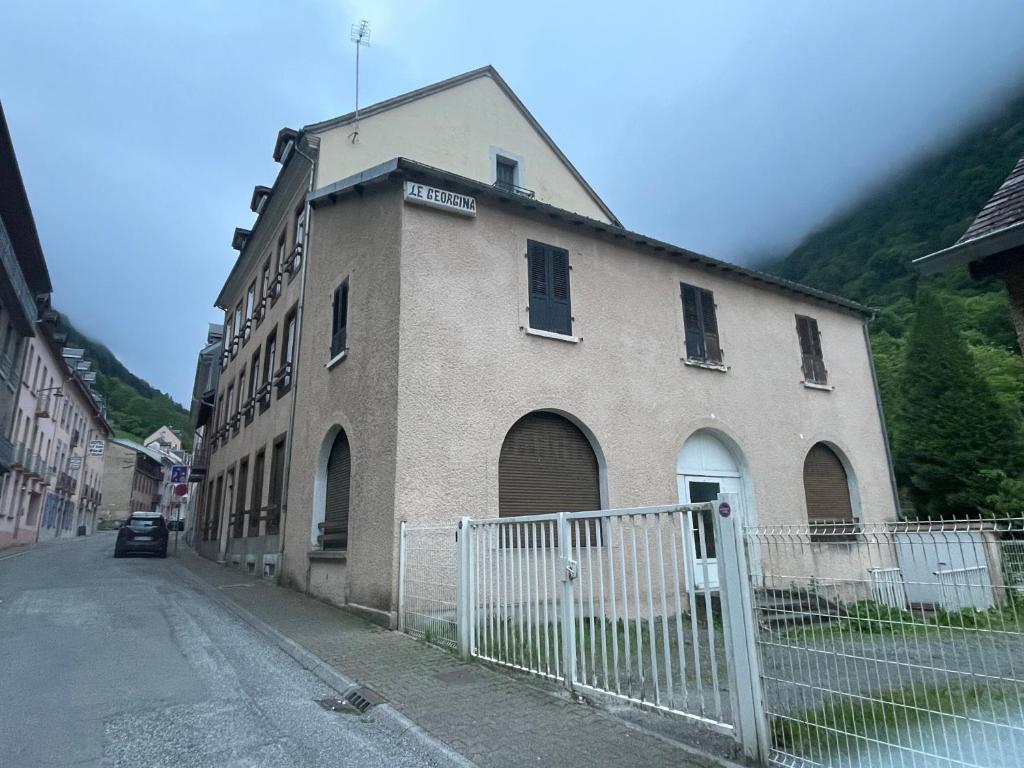een gebouw aan de kant van een straat met een hek bij Résidence Le Georgina in Cauterets