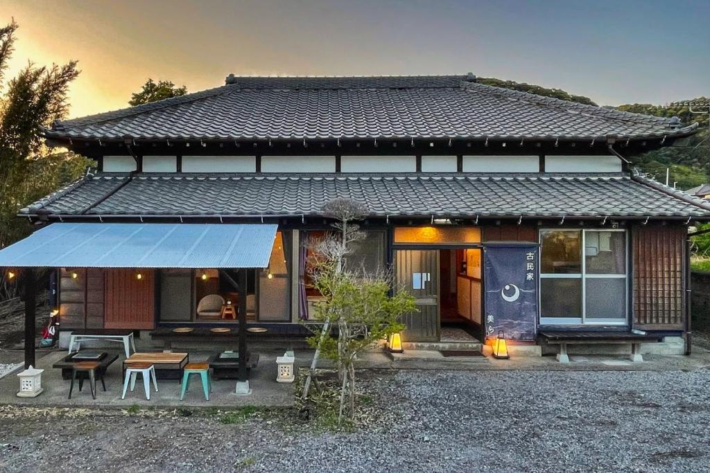 Una pequeña casa con una mesa y sillas delante de ella. en 古民家美ら 鴨川, en Kamogawa