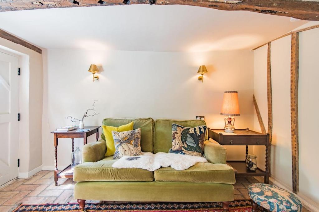 a living room with a green couch and a table at Bertie's Cottage by Keepers Cottages in Robertsbridge