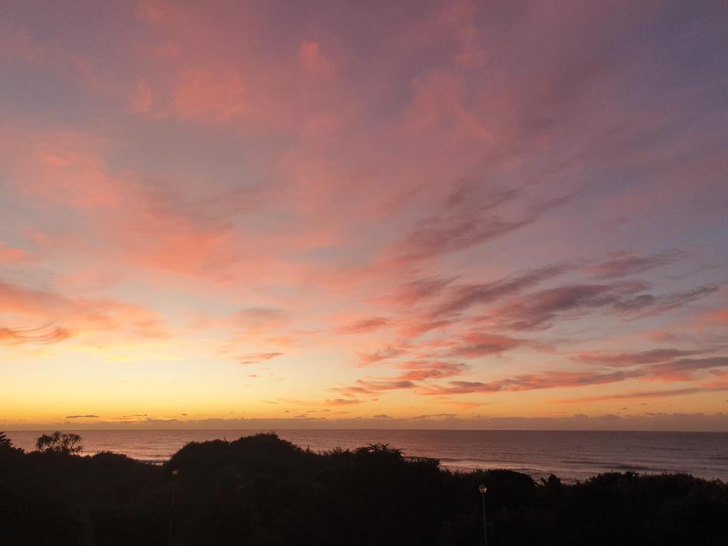 a sunset over the ocean with a cloudy sky at Deep Blue Guest House in Amanzimtoti