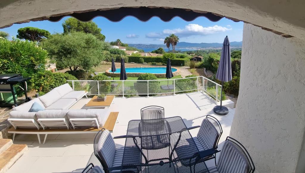 une terrasse avec un canapé et des chaises ainsi qu'une piscine dans l'établissement LE CLOS BUCCI - Golfe de Saint-Tropez - Les hauts de Grimaud, villa avec vue exceptionnelle, à Grimaud
