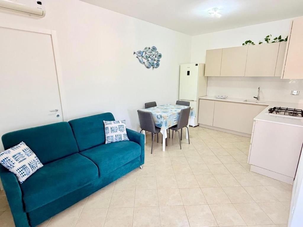 a living room with a blue couch and a kitchen at Isabel Apartment in Porto Azzurro