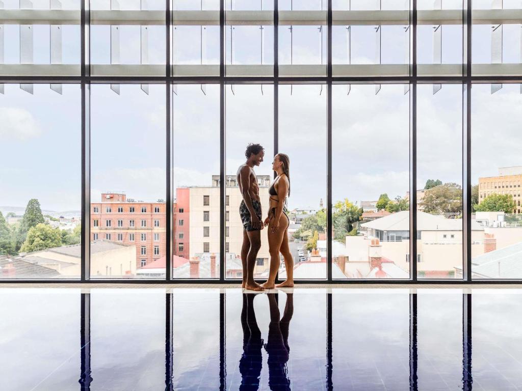 Una pareja parada frente a una gran ventana en Ibis Styles Hobart, en Hobart