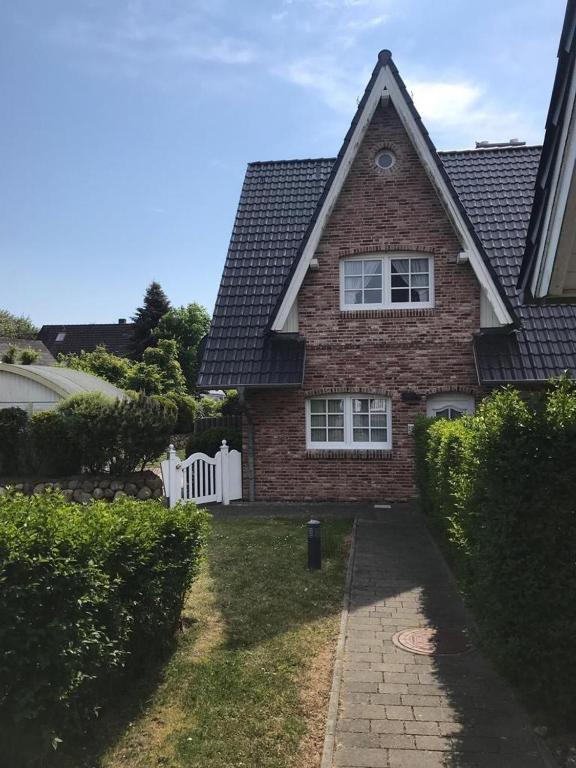 a brick house with a white fence in the yard at Leo-s-Hues in Tinnum