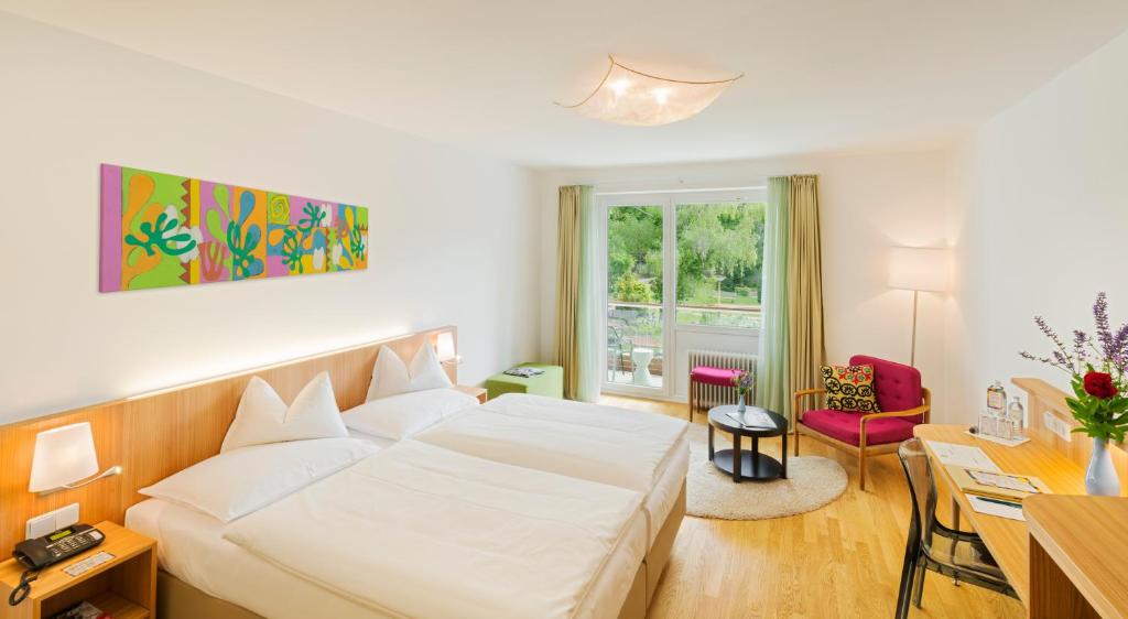 a hotel room with a white bed and a desk at At the Park Hotel in Baden