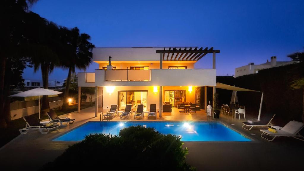 a villa with a swimming pool at night at Praia by Check-in Portugal in Albufeira