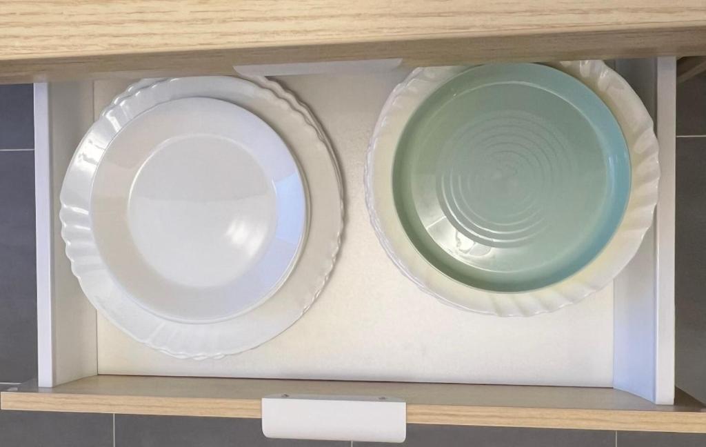 two plates sitting on a shelf in a cabinet at PARIS-MONTROUGE Magnifique Studio Appartement de 35m2 - très cosy pour 1 à 6 personnes refait à neuf - ENTIRE APARTMENT LUXIRIOUS AND WARM - Montrouge Paris 14ème - Proche Aéroport Orly & Parc Expositions Porte de Versailles FREE WIFI GRATUIT in Montrouge