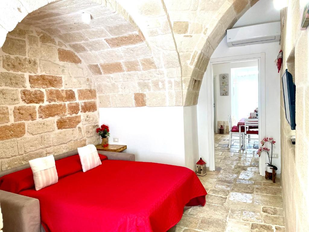 a red bed in a room with a stone wall at Antica Pietra in Polignano a Mare