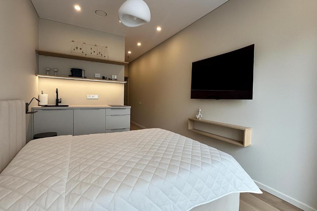 a bedroom with a white bed and a flat screen tv at Pušų natos in Druskininkai