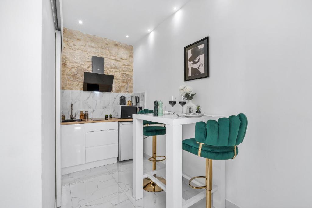 a kitchen with a table and two green chairs at Le SEPT MARTINE Hyper centre - Air-conditioned - Terrace - Quiet - Wifi - Tramway in Nice