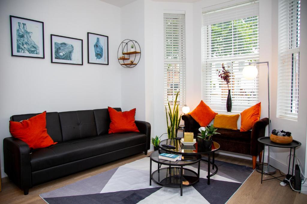 a living room with a black couch and orange pillows at SmartStay, Fast Wifi and Workspace, 3 Beds, Central, Private Parking, by Airport in Farnborough