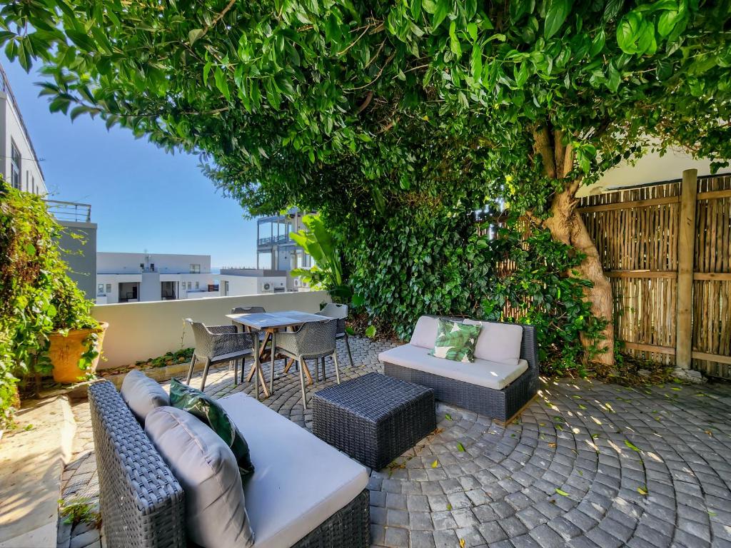 a patio with couches and a table and chairs at Oasis in Seapoint in Cape Town