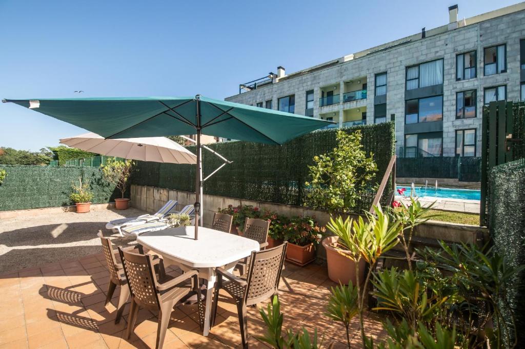 a patio with a table and chairs and an umbrella at Apto Llanes Piscina y Playa – El Recreo de Celorio in Celorio