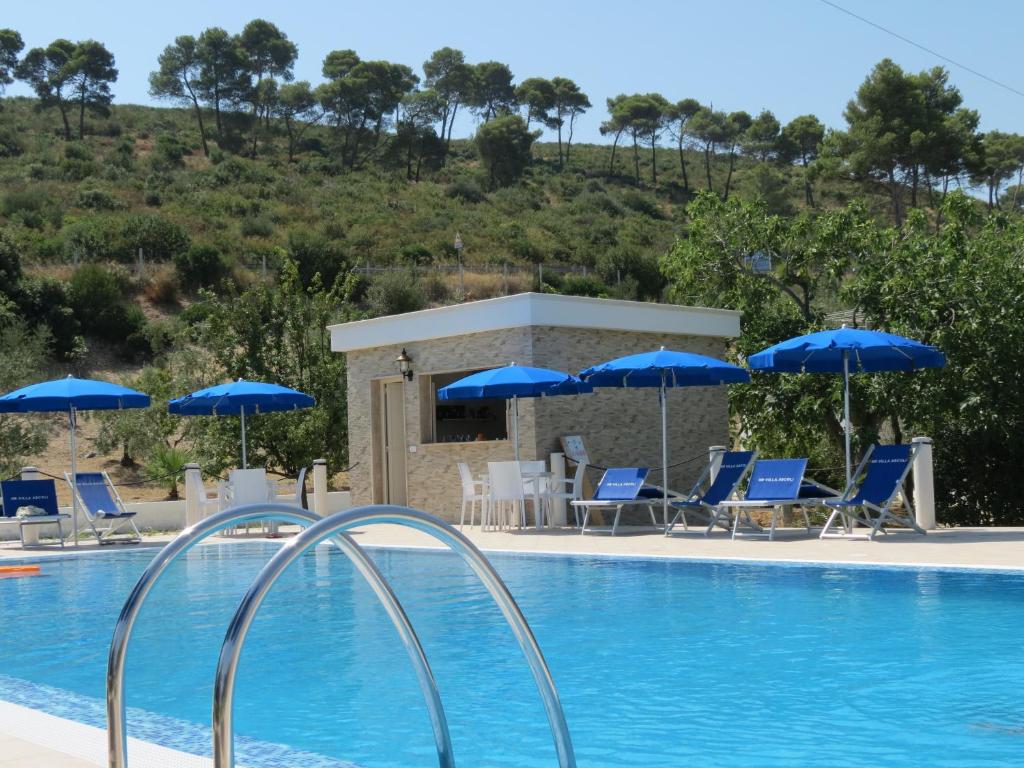 a swimming pool with blue chairs and umbrellas at Hotel Residence Villa Ascoli in Vieste
