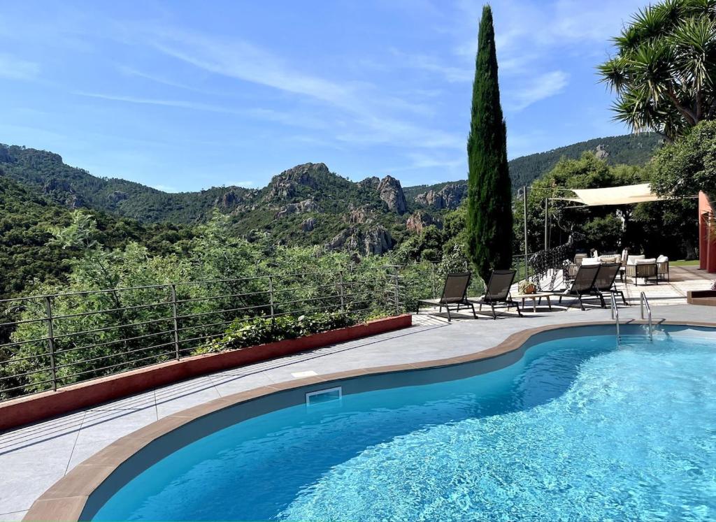 une piscine avec des chaises et des montagnes en arrière-plan dans l'établissement VillaM with heated pool, panoramic view, sea, à Mandelieu-la-Napoule