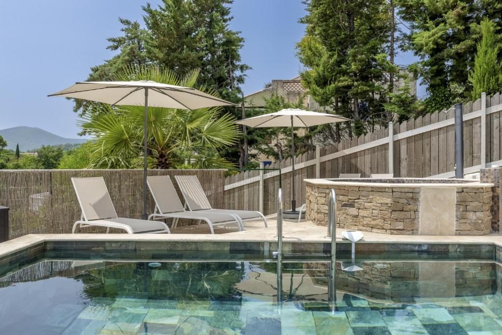 - une piscine avec 2 chaises longues et des parasols dans l'établissement SOLEIA - Vue Mer, Piscine & Jardin privé, Parking, à Roquebrune-sur Argens