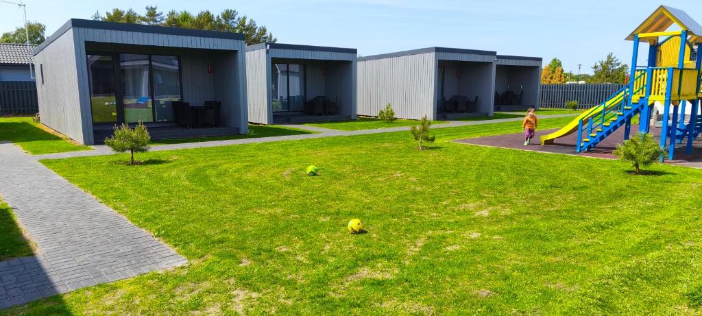 a child standing in a yard with a playground at Audronašų Vilų Nameliai in Šventoji