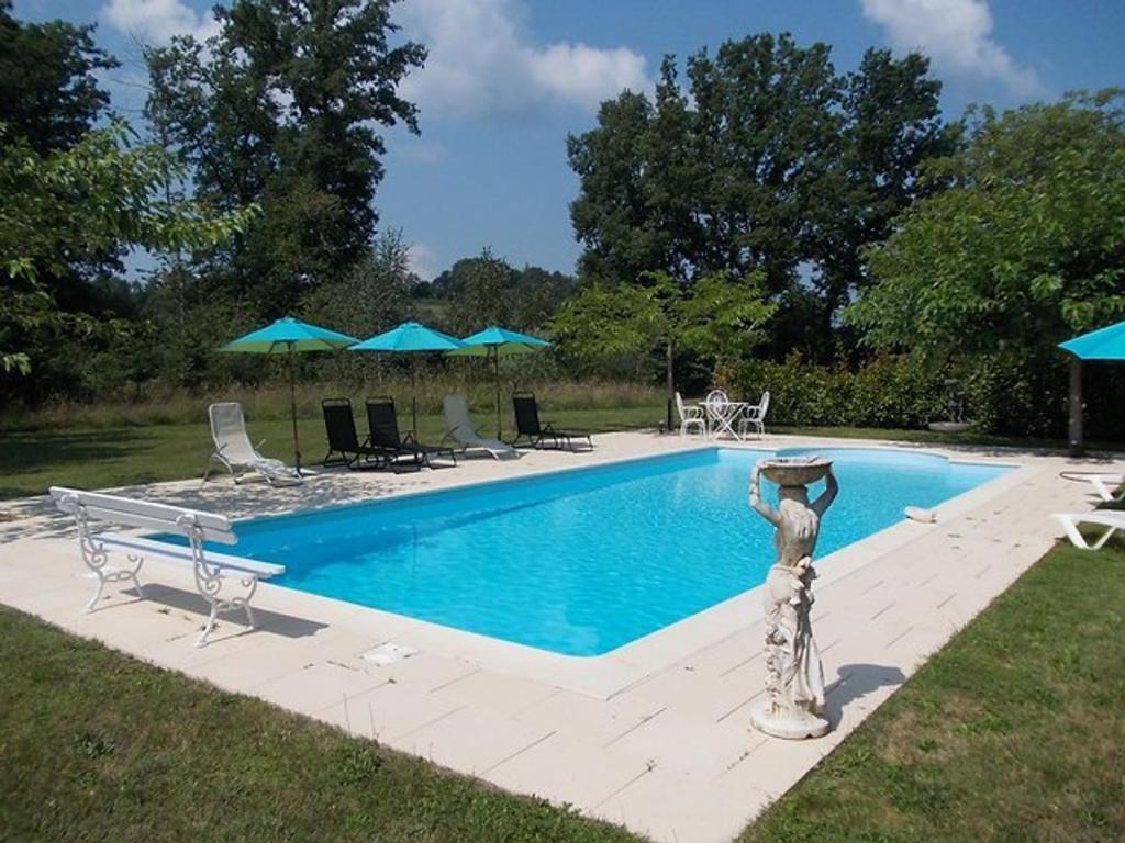 une piscine avec chaises et parasols dans une cour dans l'établissement Maison campagne avec piscine privée en Périgord, pour 6 personnes - FR-1-824-14, à Siorac-en-Périgord