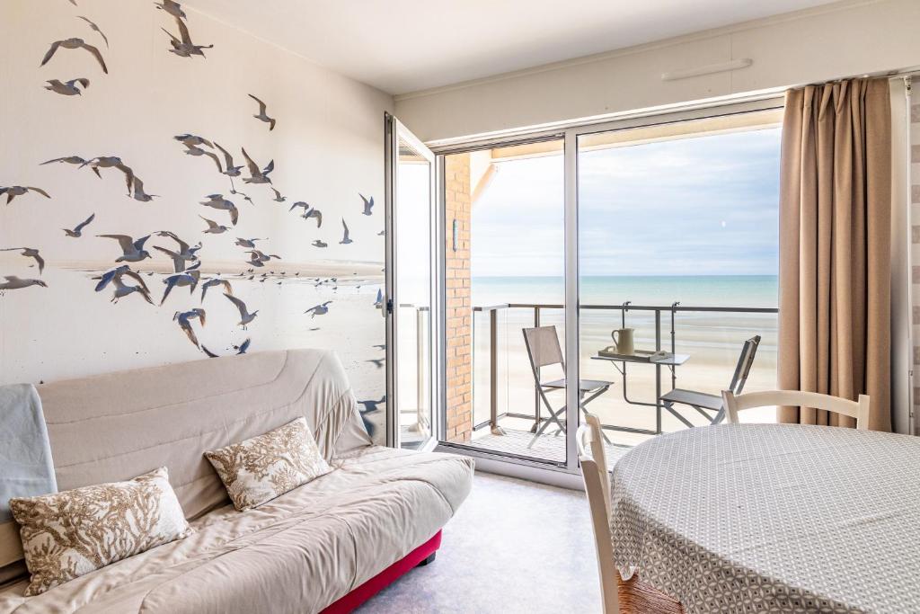 une chambre avec un lit et un balcon avec des oiseaux sur le mur dans l'établissement Résidence le Nautica - au pied de la plage, à Bray-Dunes