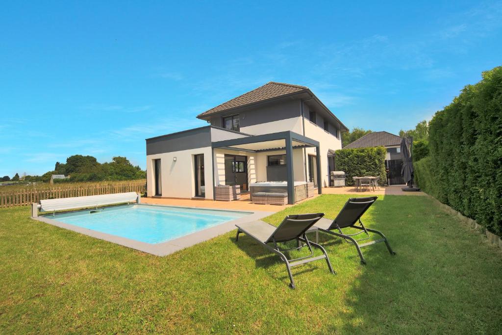 una casa con piscina e due sedie nel cortile di La Villa Sainghin - Piscine et Jacuzzi Privé a Sainghin-en-Mélantois