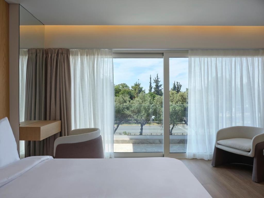 a hotel room with a bed and a large window at Nur Riviera Aparthotel in Athens