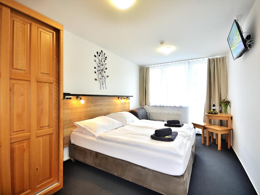 sypialnia z dużym białym łóżkiem i drewnianymi drzwiami w obiekcie Hotel Resort Luna w mieście Ledeč nad Sázavou