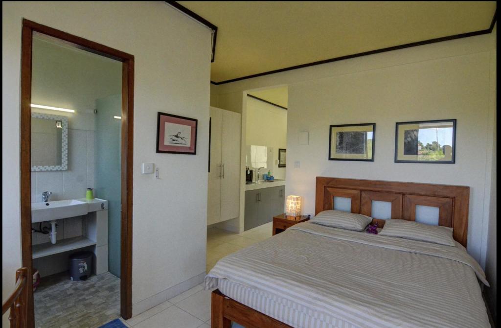 ヌサドゥアにあるRumah Gadang Bali Apartmentsのベッドのある寝室と洗面台のある浴室