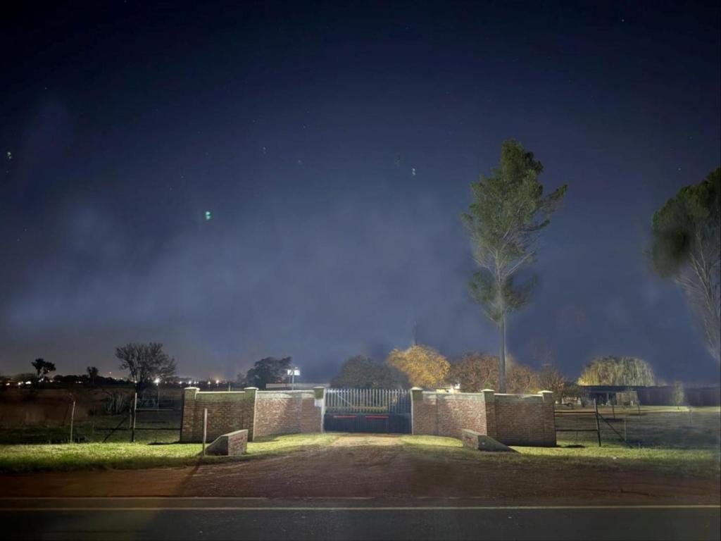 a park with a bench and a tree at night at The Grove in Potchefstroom