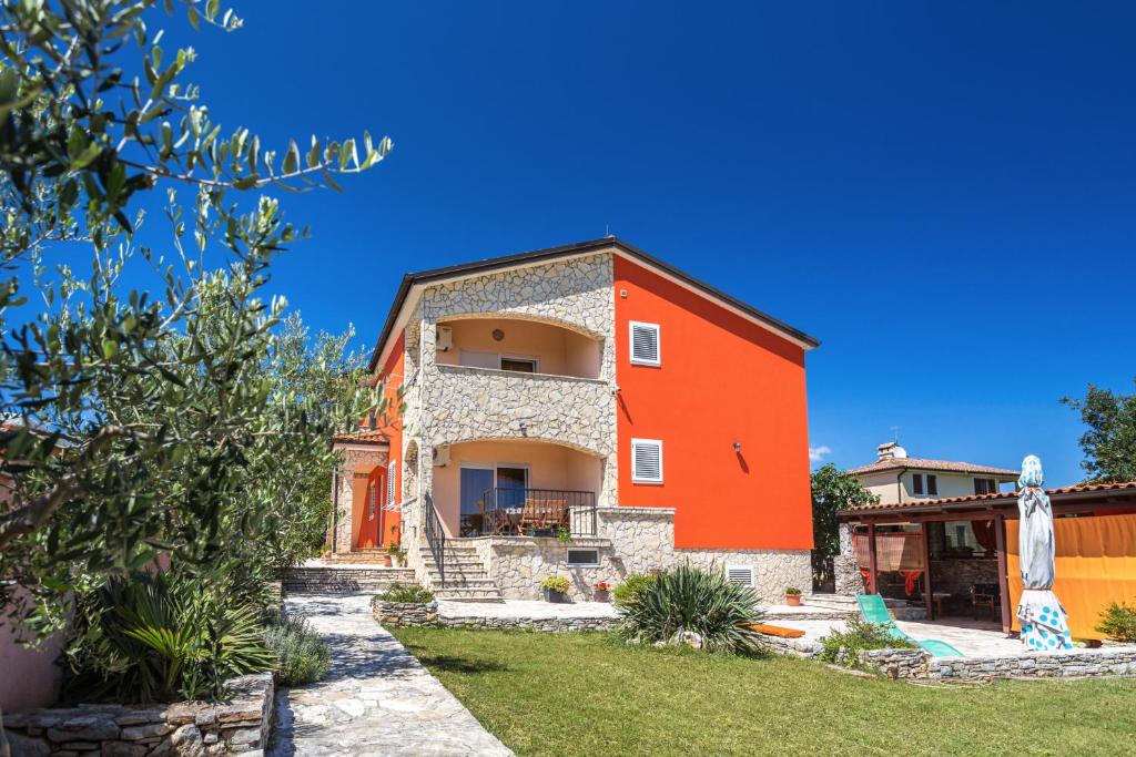 una casa con una pared roja y un patio en Apartments Villa Orange, en Medulin