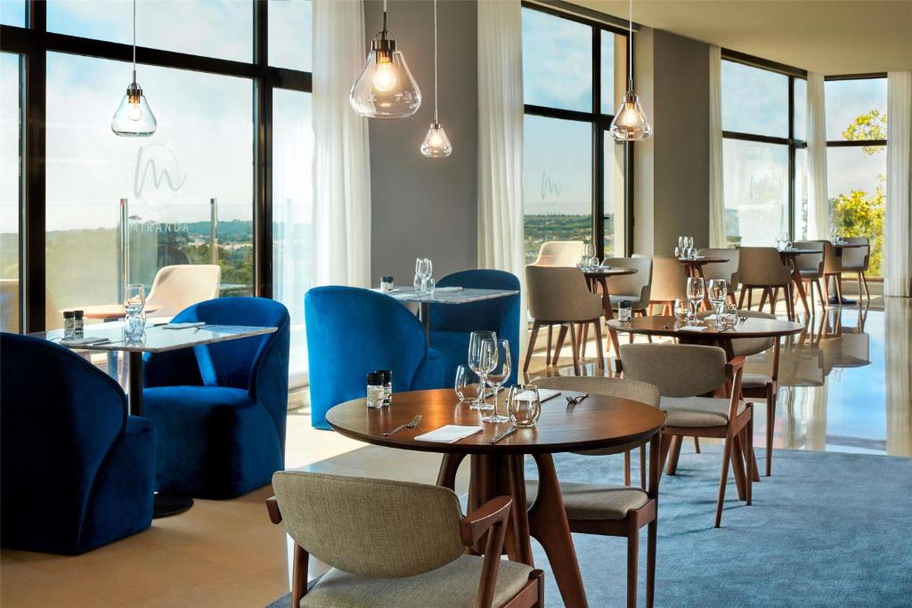a restaurant with tables and chairs and windows at NH Sintra Centro in Sintra