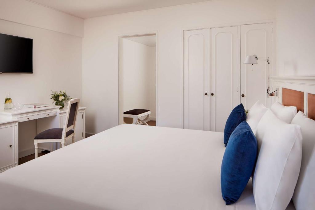 a bedroom with a white bed with blue pillows at NH Sintra Centro in Sintra