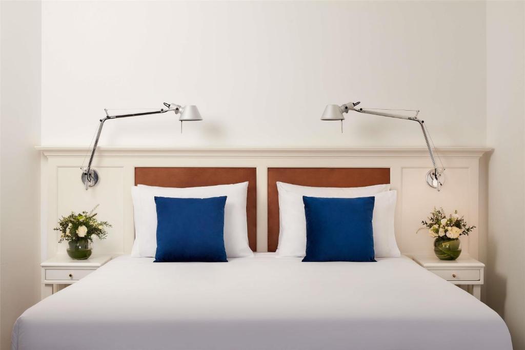 a bedroom with a white bed with blue pillows at NH Sintra Centro in Sintra
