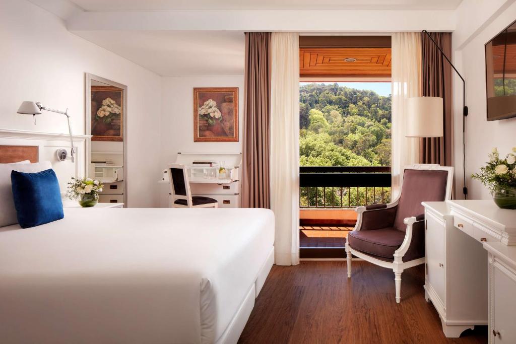 a hotel room with a bed and a chair and a window at NH Sintra Centro in Sintra