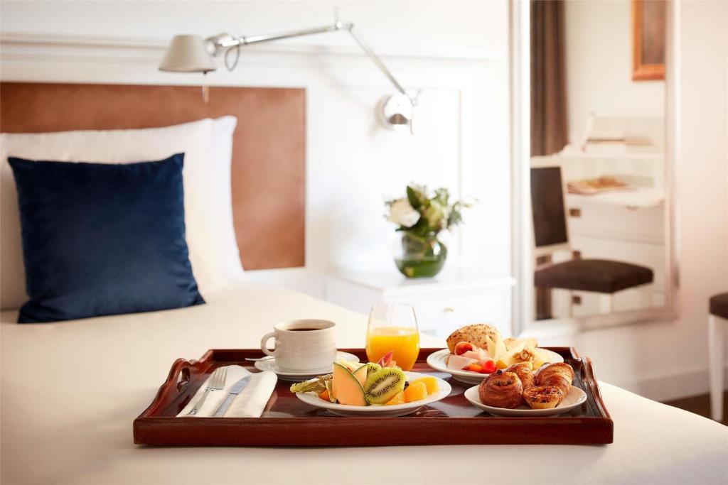 a tray with breakfast foods on a bed at NH Sintra Centro in Sintra