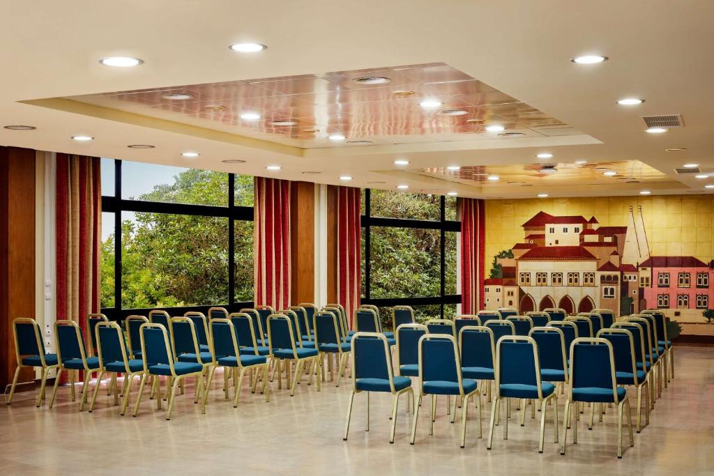 a conference room with blue chairs and a wall of windows at NH Sintra Centro in Sintra
