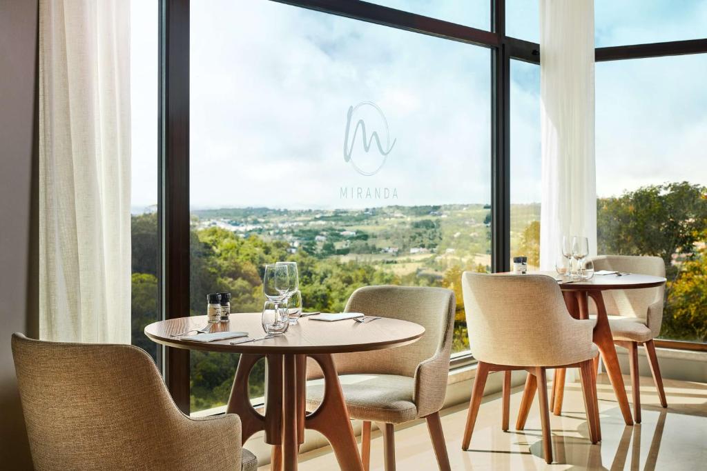 a restaurant with two tables and chairs and a large window at NH Sintra Centro in Sintra