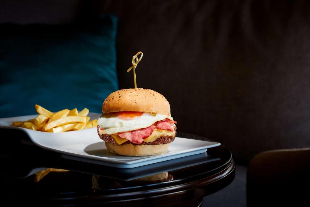a sandwich on a plate next to a plate of fries at NH Sintra Centro in Sintra